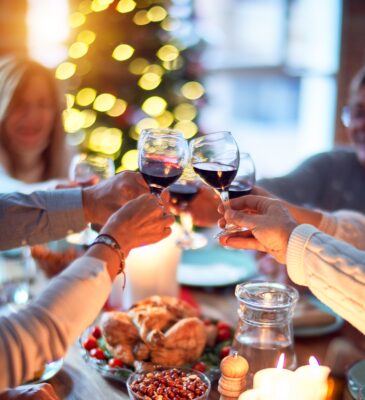Five people raising their glasses to toast a Christmas dinner.